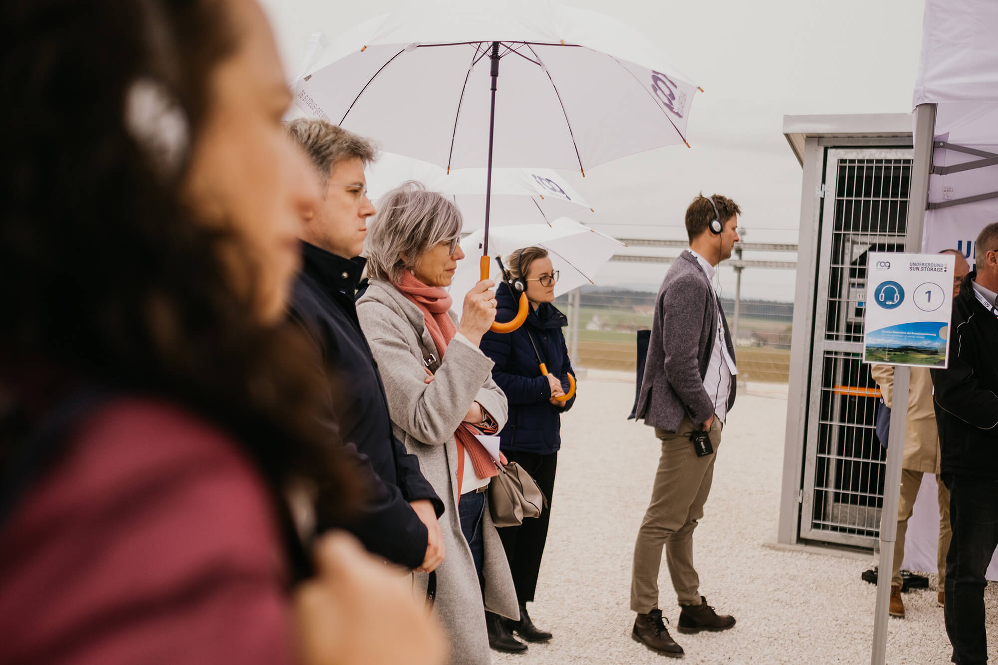 Visitors with umbrellas and headphones at RAG international event